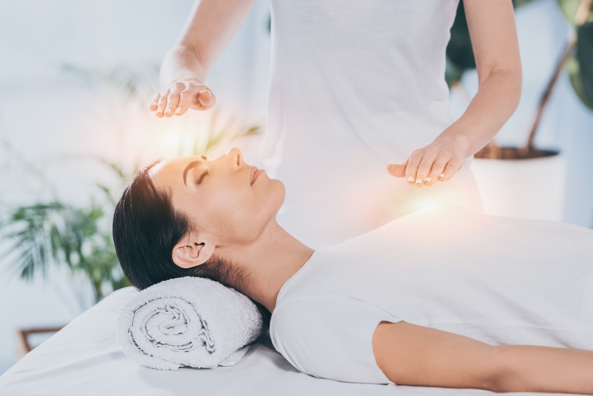 Seitenansicht der ruhigen jungen Frau, die Reiki-Heiltherapie auf Kopf und Brust erhält